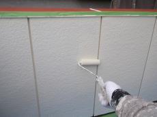 バルコニー腰壁内側（金属サイディング）の上塗りの様子です。日本ペイントの1液ファインウレタンを使用しています。