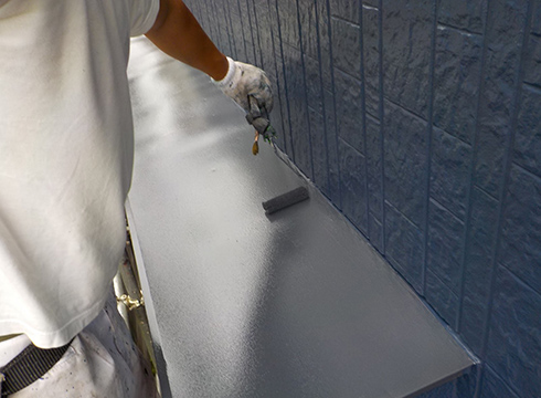 霧除け庇の上塗り塗装の様子です。塗料は、日本ペイントの1液ファインウレタンを使用していて、色番号は「N25（屋根色合わせ）3分艶」です。