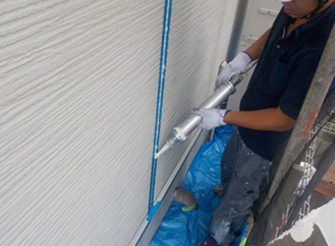 外壁の既存サイディング目地の密着剤塗装を行っています。材料はサンスターペンギンシールを使用しています。
